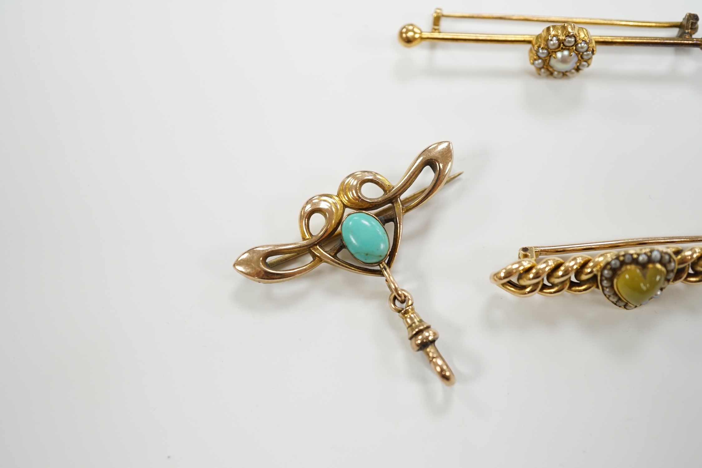 An Edwardian Art Nouveau 9ct gold and turquoise set brooch, width 38mm, a yellow metal (stamped 20) and seed pearl cluster set bar brooch and one other yellow metal and gem set brooch.